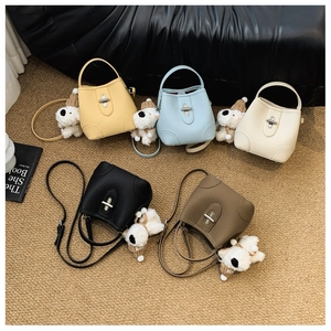 Detail of five pebble grain leather bucket bags with metal clasps and plush dog charms