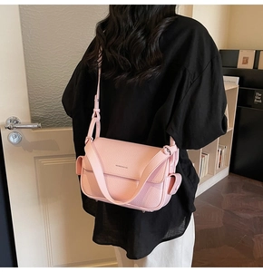 Close-up of a light pink lychee pattern leather shoulder bag on model in cozy interior