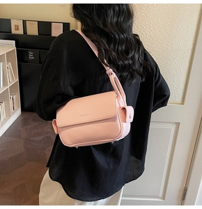 Close-up of pink litchi grain leather crossbody bag with flap and adjustable strap