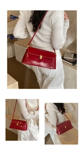 Close-up of vintage red leather shoulder bag with elegant gold metal buckle and stitching