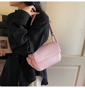 Pink litchi texture leather shoulder bag with logo detail shown on a female model