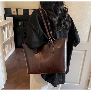 Dark brown faux leather tote bag showing model fit and shoulder strap adjustment detail