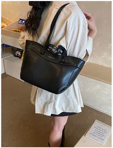 Minimalist black PU tote bag shown worn on shoulder with slim straps and matte texture