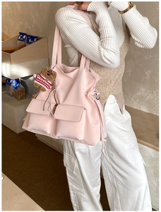 Dettaglio borsa tote in tela rosa chiaro con tasche frontali e ciondolo a forma di orso