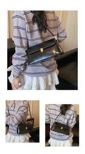 Detail of a black leather underarm bag with gold metal square lock and long strap