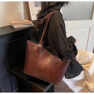Detailed view of deep brown faux leather tote with vintage oil wax finish and metallic buckle