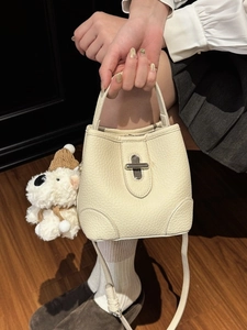 Minimalist cream white lychee leather bucket bag with silver lock and plush puppy pendant