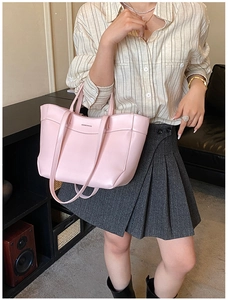 Detailed view of pink leather tote bag with logo on a model with beige shirt