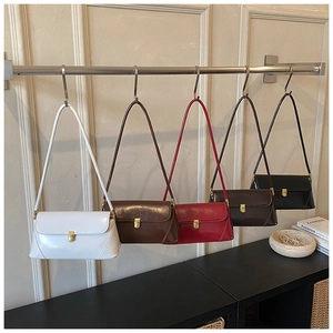 Detail showing five colors of baguette bags with gold metal clasps on a display rack