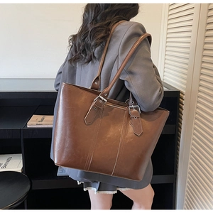Detail of dark brown leather tote bag with silver adjustable buckles and smooth finish