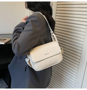 Detail of cream white lychee leather shoulder bag featuring a classic flap and logo