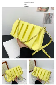 Detail view of light yellow pleated cloud bag with golden chain and pearl ornaments