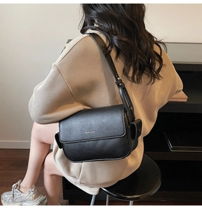 Detail of black lychee grain leather crossbody bag with adjustable shoulder strap on model
