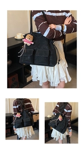 Detail of black tote bag featuring dual front flap pockets and a cute teddy bear charm