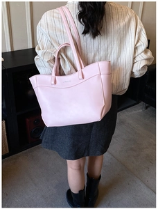 Detailed back view of pink leather tote bag featuring a metallic logo and adjustable strap
