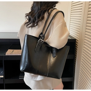 Close-up of black leather tote bag with metal buckle and fine stitching details