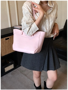 Pale pink tote bag shown in a lifestyle scene with a smooth faux leather finish