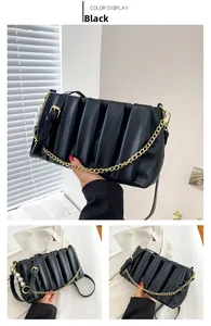Detail of black pleated square bag with large pearls, gold chain and shoulder strap