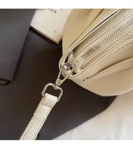 Detail of silver-tone metal hardware and lychee grain leather on cream bucket bag
