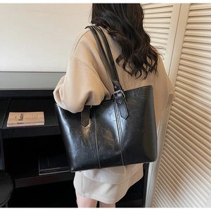 Detail of black faux leather tote bag with silver adjustable strap buckle for women