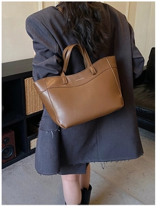 Detail of dark brown faux leather tote bag with fine texture and sturdy handles