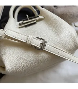 Detail view of white pebbled leather bag with adjustable silver buckle strap and metal clasp