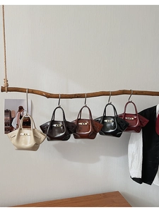 Fünf Vintage Handtaschen in verschiedenen Farben an Holzzweig mit goldenen Schlössern