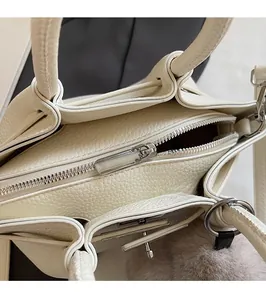 Close-up of creamy white leather bucket bag featuring silver zipper and hardware details