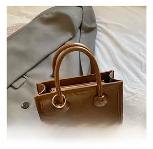 Detail of retro dark brown leather handbag featuring dual handles and a beaded charm accessory