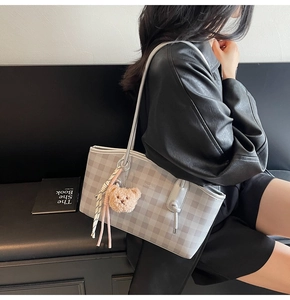 Detail of light gray gingham tote bag with cute bear charm and striped ribbon accent