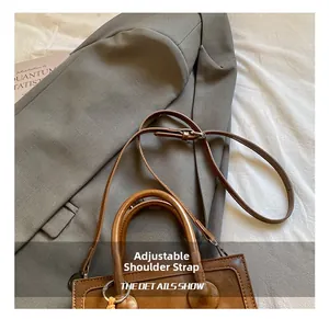 Detail showing brown leather baguette bag with adjustable strap and retro top handle