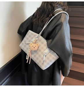 Checkerboard tote bag with bear charm and tassel shown in a lifestyle model shot