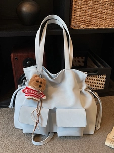 Borsa tote celeste in ecopelle con doppie tasche frontali e ciondolo a forma di orsetto