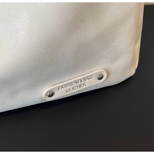 Vue détaillée de la texture du cuir blanc avec rivets métalliques et logo en relief