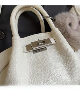 Detail of silver twist lock and leather strap on off-white textured shoulder bag