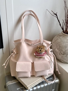 Borsa tote rosa in ecopelle con tasche frontali e ciondolo a orsetto su una valigia
