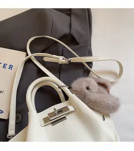 Detailed view of white pebble leather bucket bag with silver twist lock and bunny charm