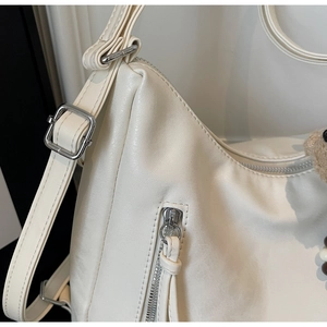 Détail du sac à bandoulière en similicuir blanc cassé avec zip argenté et pendentif