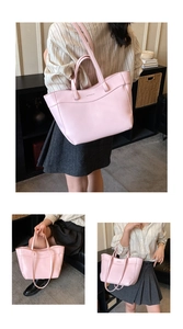 Detail of a large pink leather tote bag featuring a subtle embossed logo and dual handles