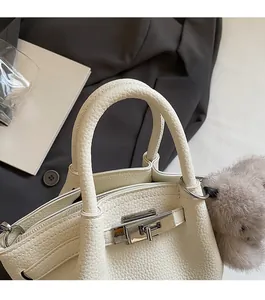 Close-up of beige leather tote bag with lychee grain texture and silver hardware