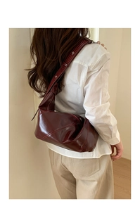 Deep burgundy leather hobo bag with geometric stitching and metal eyelet wide shoulder strap