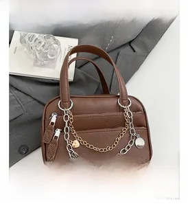 Detail of brown litchi leather Boston bag with metallic chain and heart charm