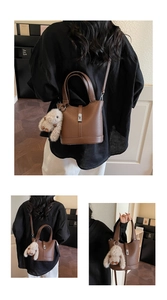 Detail view of brown lychee grain leather bucket bag with a cute plush bunny pendant