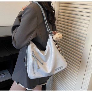 Détail du sac hobo en similicuir bleu clair avec poche zippée et breloque ours doux