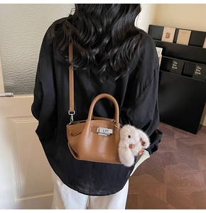 Brown litchi grain leather bucket bag with silver lock and plush bunny charm on a model