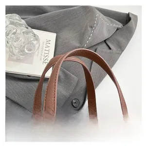 Close-up of brown lychee grain leather handbag featuring dual handles and metal zipper