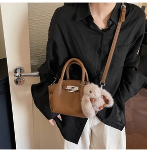 Brown lychee pattern leather tote bag with silver lock and plush bunny charm on a model