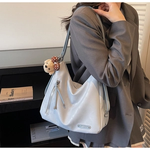 Détail d'un sac hobo en cuir souple bleu clair avec breloque ours et fermeture éclair