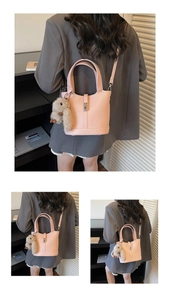 Detail of pink lychee leather bucket bag featuring a plush rabbit pendant and metallic lock