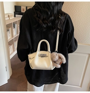 Rear view of a white lychee grain leather handbag with a plush rabbit charm and metal lock